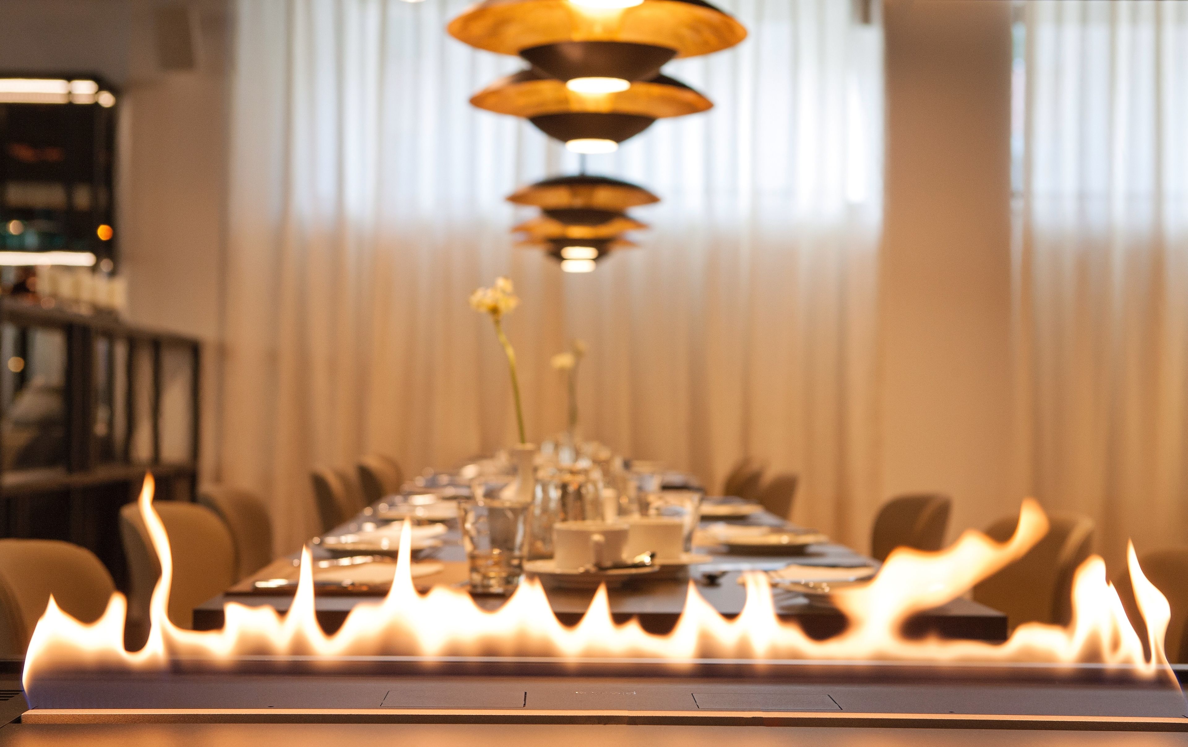 Une table à manger au design moderne, agrémentée d’un élément décoratif central en forme de flamme.