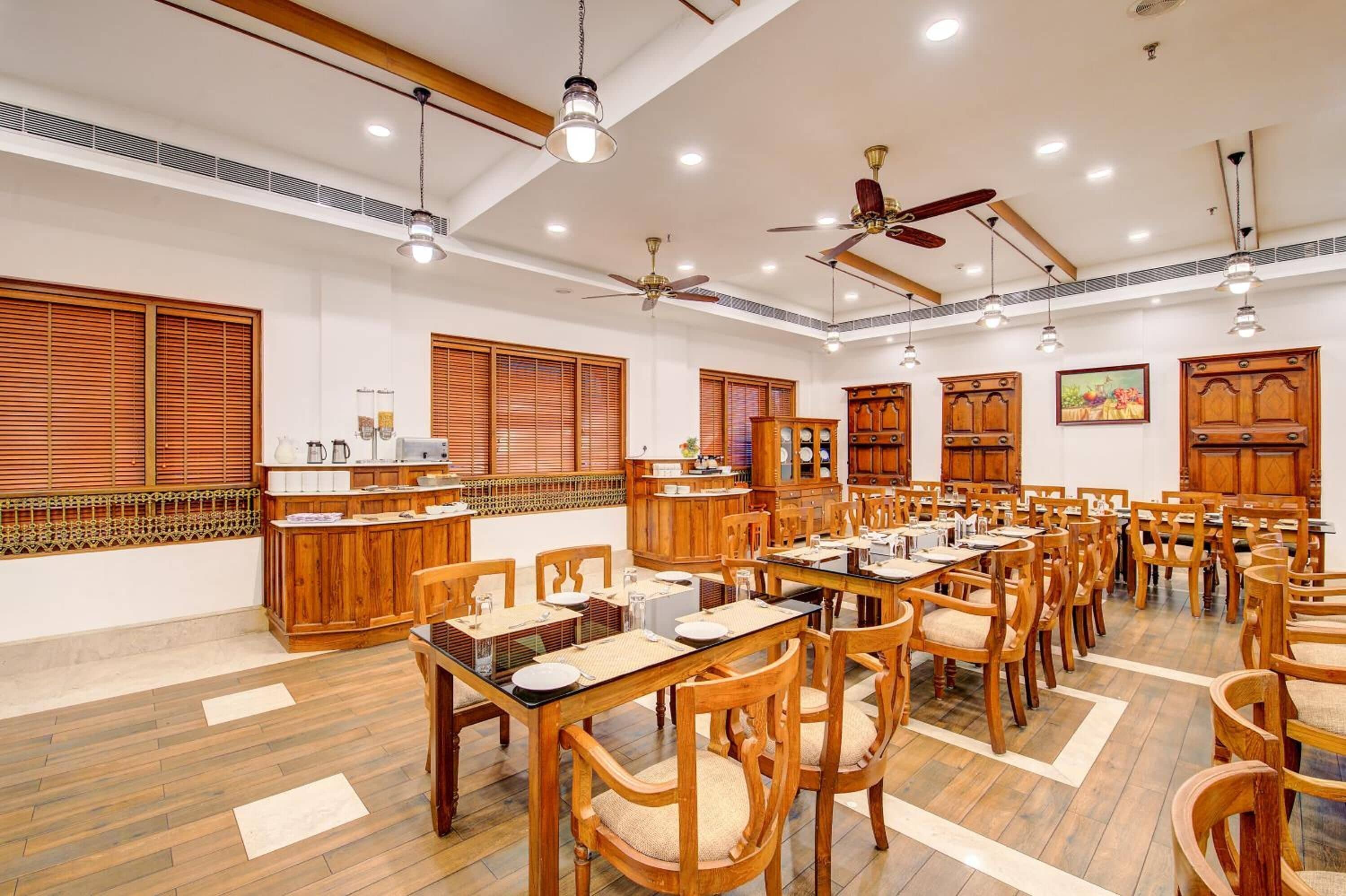 A spacious dining area with wooden tables and chairs, ceiling fans, and recessed lighting.
