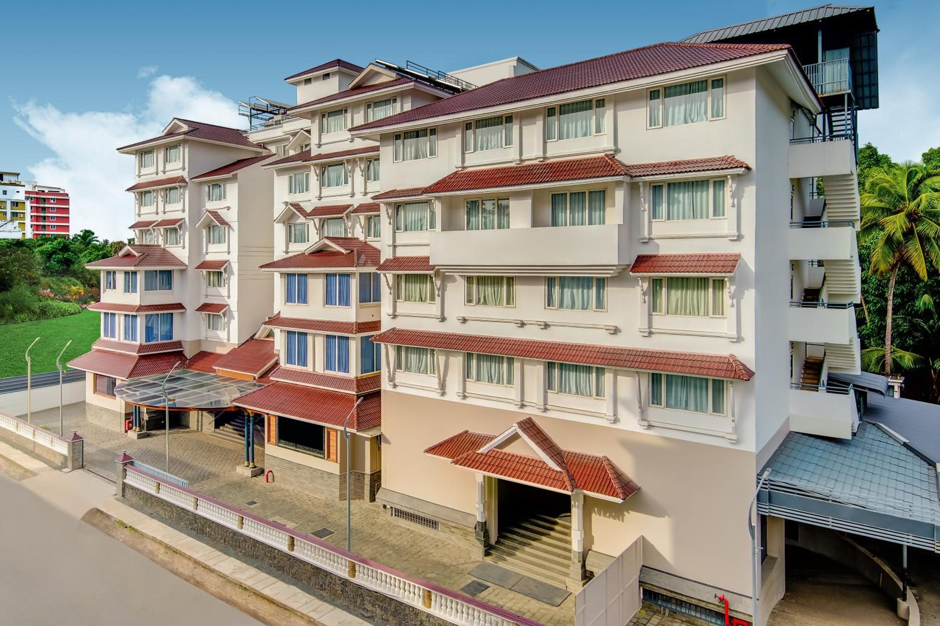 A multi-story hotel with a flat roof, balconies, and a covered entrance area.