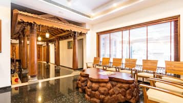 A lobby with a traditional wooden reception desk, a large window with blinds, and a polished marble floor.