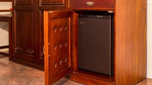 A wooden cabinet with a drawer and a small black refrigerator. - Sterling Guruvayur (Chavakkad)