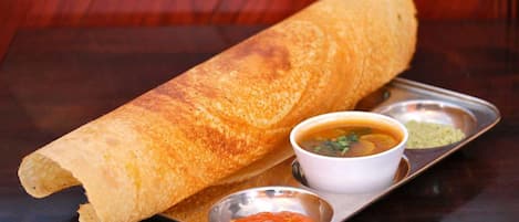 Una dosa acompañada de dos guarniciones sobre una bandeja metálica.