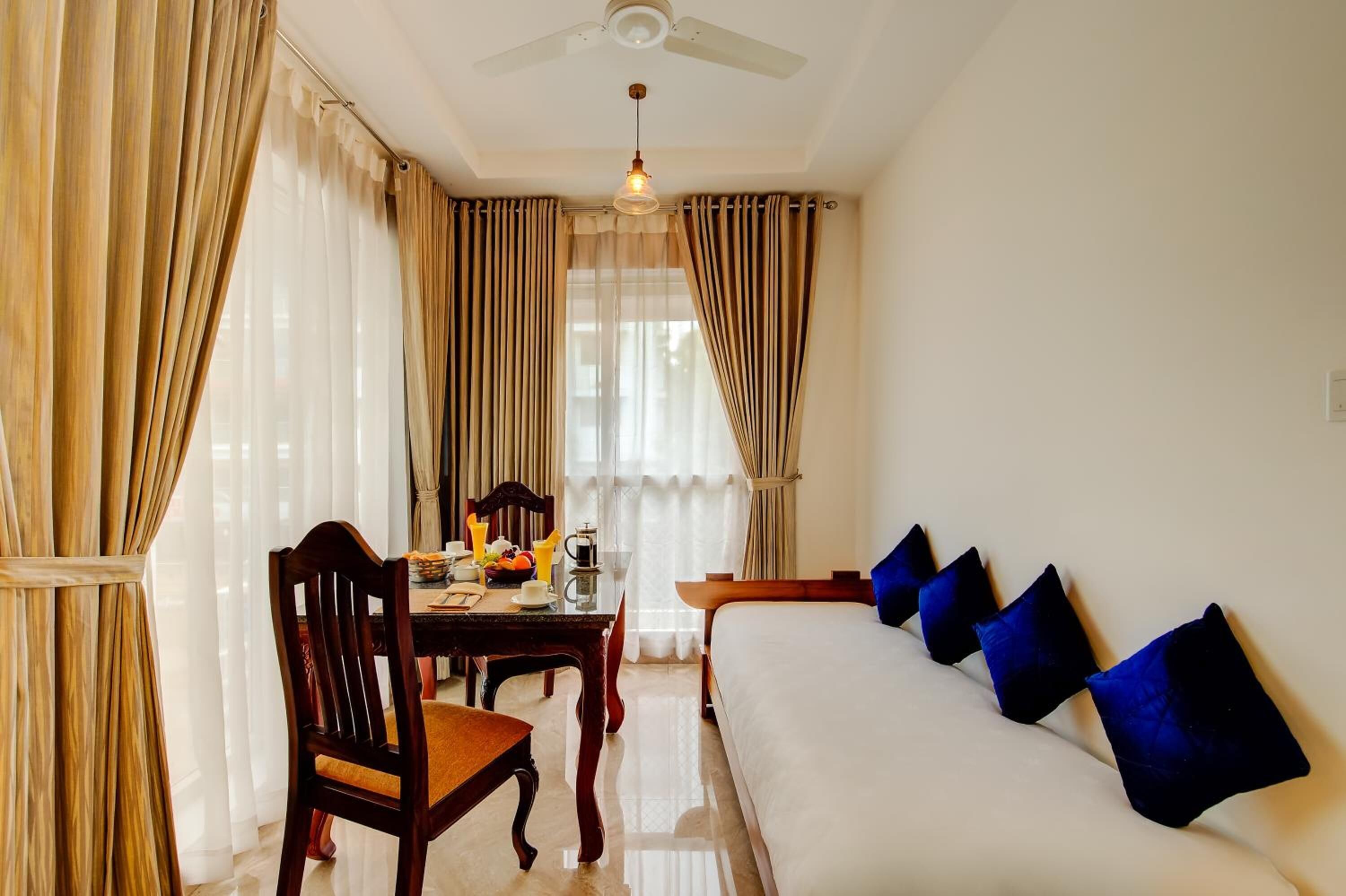 Une chambre d’hôtel avec un lit, une table où le petit-déjeuner est servi, et des rideaux.