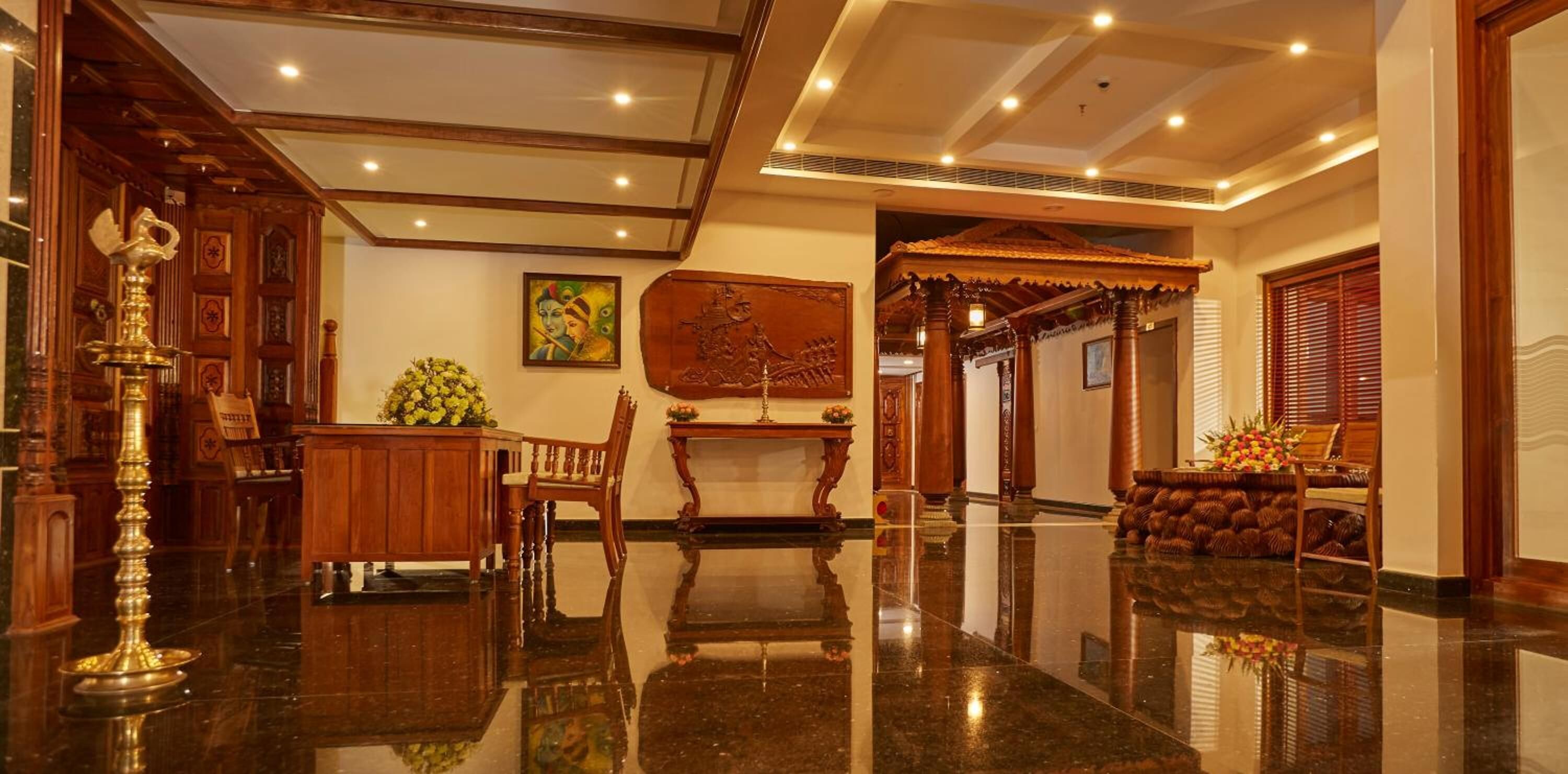 A spacious lobby with polished marble floors, wooden furniture, and traditional decor.