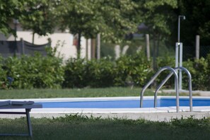 Guests can enjoy a refreshing swim in the pool surrounded by lush greenery and a secure fence.