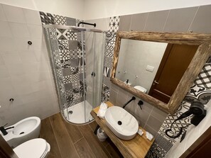 A bathroom with a glass shower enclosure, a white sink, and a wooden vanity. - Agriturismo Cupello (Cagnano Amiterno)