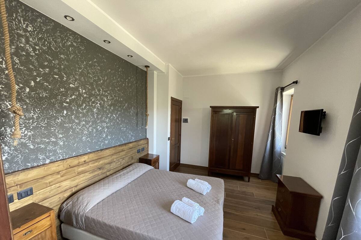 A bedroom with a large bed, wooden headboard, a wardrobe, and a mirror on the wall.
