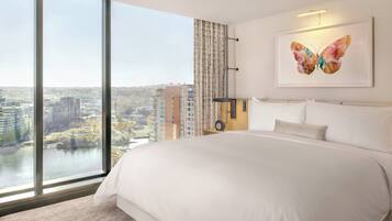 A hotel room with a large bed, a view of the city, and a butterfly artwork on the wall.