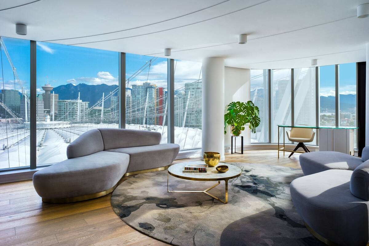 Un moderno salón con un amplio ventanal que ofrece vistas a la ciudad, incluyendo un puente y montañas.