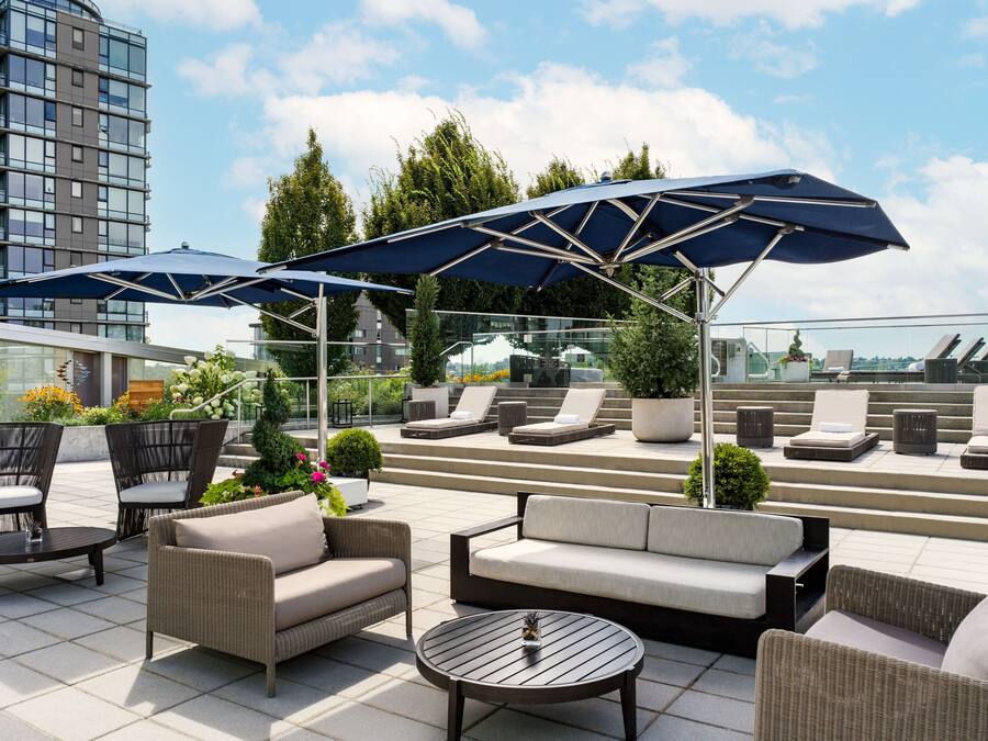 Eine Dachterrasse mit Außenmöbeln, Sonnenschirmen und Blick auf die Stadtlandschaft.