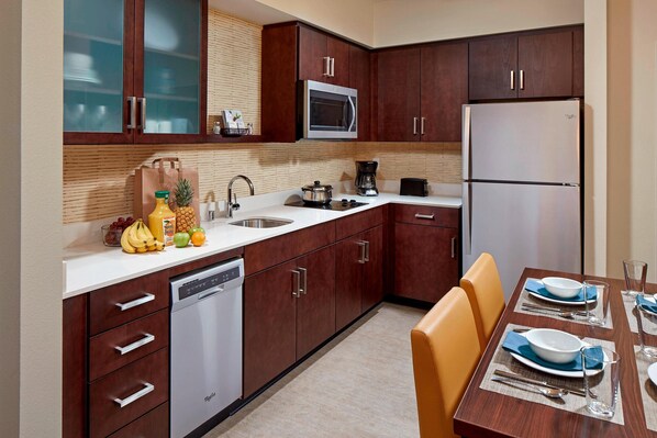 Una cocina moderna con armarios de madera, microondas integrado y refrigerador de acero inoxidable.