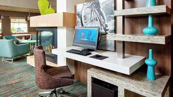 A modern hotel room with a desk, computer, and seating area.