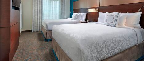 A hotel room with two beds, a TV, and a large window with curtains.