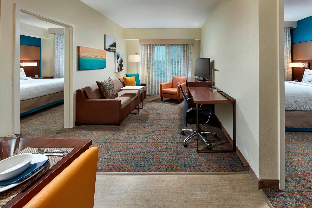 A hotel room with a bed, a sofa, a desk, and a television.
