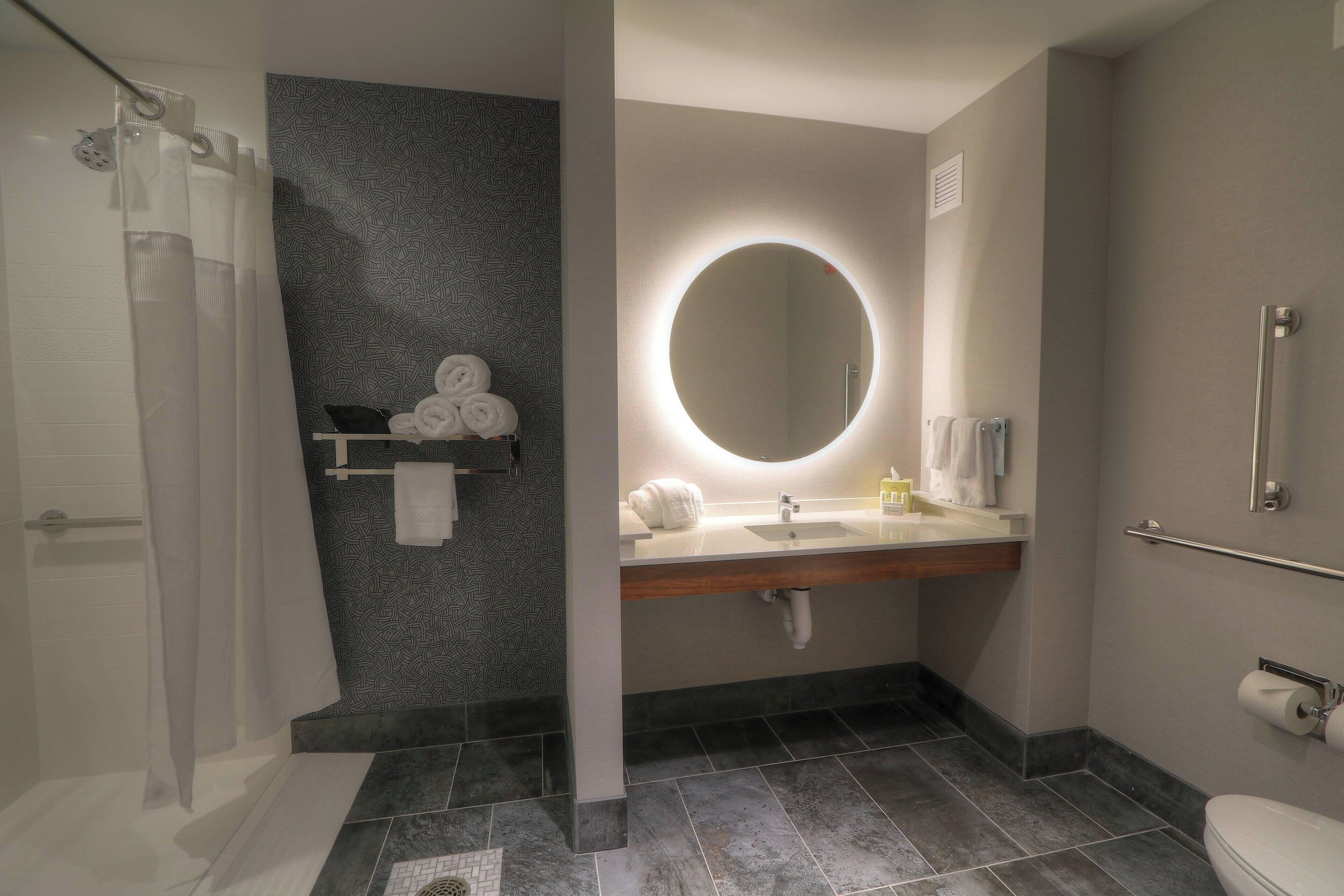A modern bathroom with a shower, a vanity with a mirror, and a toilet.