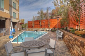 A pool area with a table and chairs, surrounded by a brick wall and trees. - Fairfield Inn & Suites by Marriott Gatlinburg Downtown (Gatlinburg)