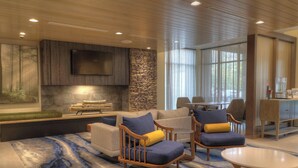 A modern living room with a stone accent wall, a flat-screen TV, and a large window.