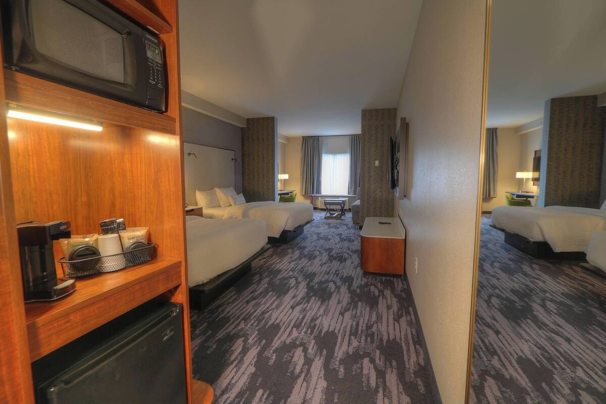 Une chambre d’hôtel avec deux lits, un four à micro-ondes, une machine à café et une petite table.