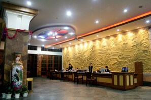 A reception area with a decorative wall, a large vase, and several computers. - Xinxing Garden Hotel (Sanya)
