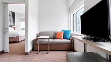 Ein modernes Hotelzimmer mit einer Couch, einem Fernseher und einem Schreibtisch.