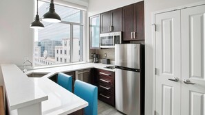 Una cocina moderna con electrodomésticos de acero inoxidable, encimera blanca y sillas azules.