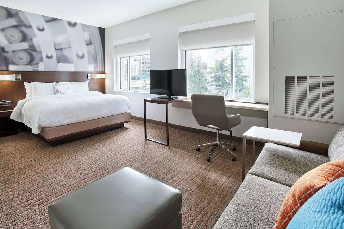 Een hotelkamer met een bed, een bureau met een computer, een stoel en een bank.