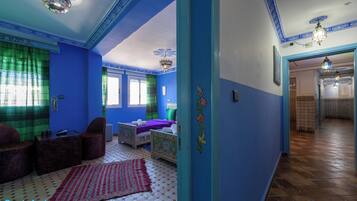 A room with a blue and white color scheme, a bed, a chair, a table, and a patterned rug.