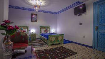 A room with a bed, a sofa, a TV, and a decorative ceiling light.