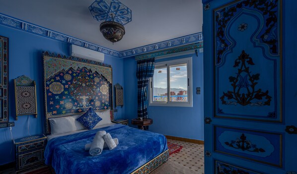 A room with a large bed, a decorative ceiling, and a view through a window. - Puerta Azul (Chefchaouen)