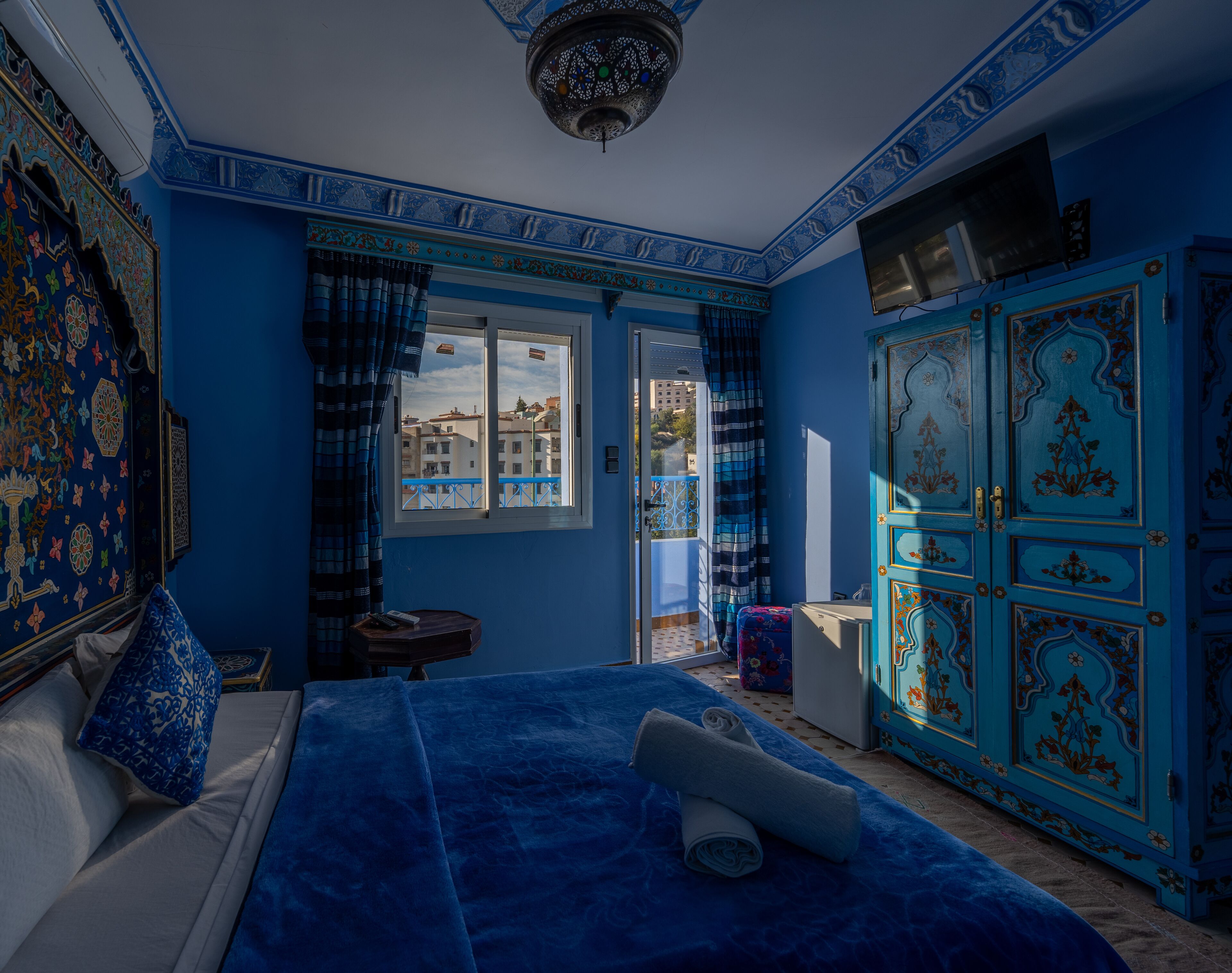 Una habitación con una cama, un armario, una ventana y una puerta.