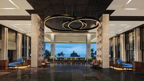 A spacious lobby with a modern chandelier, seating arrangements, and a view of the outdoors.