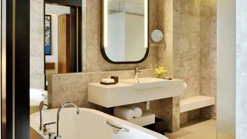 Un baño moderno con una bañera independiente, un espejo grande y un tocador con lavabo y perchero.