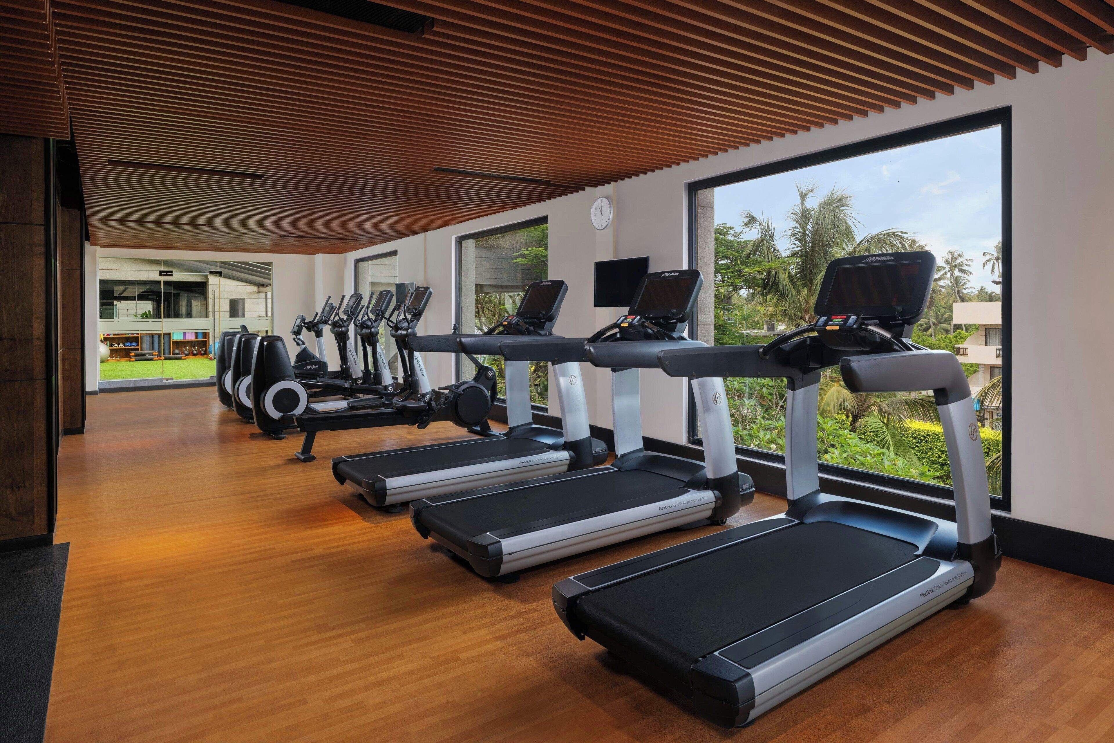 Une salle de sport équipée de tapis de course, de vélos d’exercice et de poids.