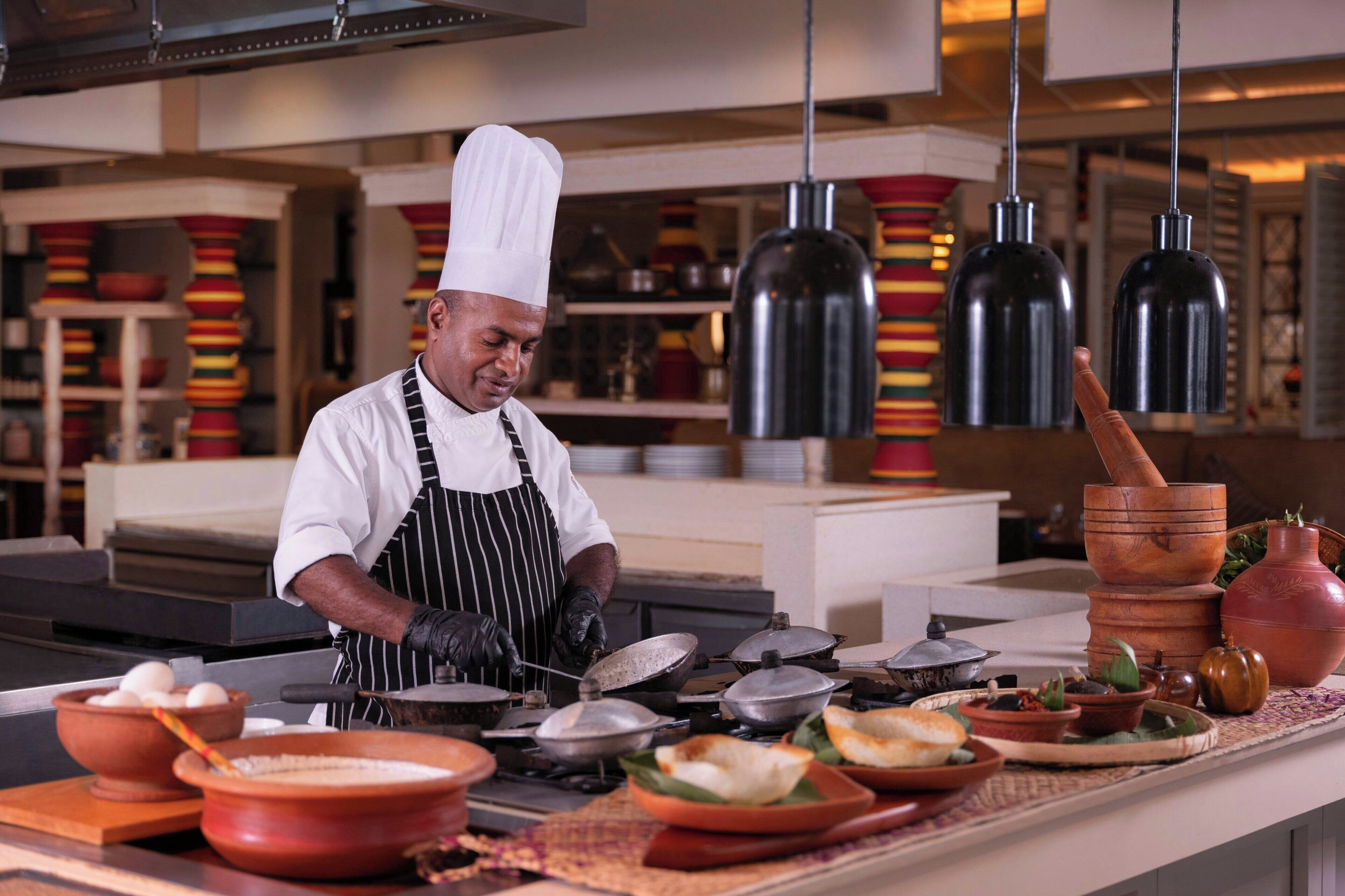 A chef in a professional kitchen with various cooking utensils and ingredients.