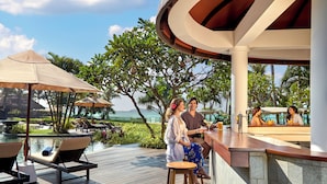 A poolside bar area with lounge chairs, umbrellas, and a view of the water.