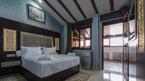 A hotel room with a large bed, a small desk, a refrigerator, and a view of the outside. - Hotel Jibal Chaouen (Chefchaouen)