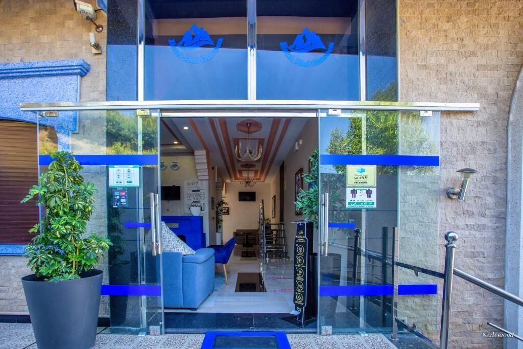 L’entrée d’un hôtel, avec une porte en verre, un comptoir d’accueil et un espace salon à l’intérieur.