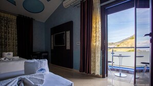 A hotel room with a bed, a desk, a TV, and a balcony with a table and chairs. - Hotel Jibal Chaouen (Chefchaouen)