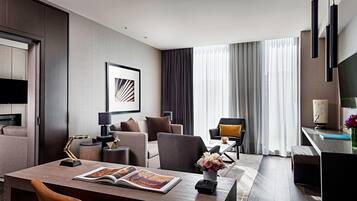 Een moderne hotelkamer met een zithoek, een loungeset, een salontafel en een televisie.