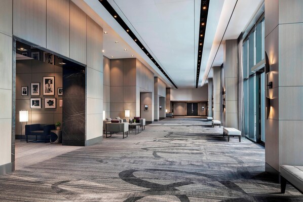 Un moderno vestíbulo de hotel con piso alfombrado, zonas de estar y cuadros enmarcados en las paredes.