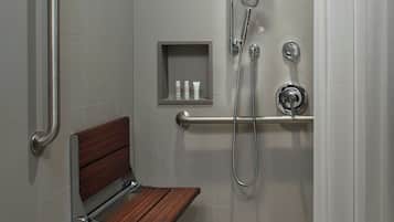 A shower area with a grab bar, a shelf with toiletries, and a wooden bench.