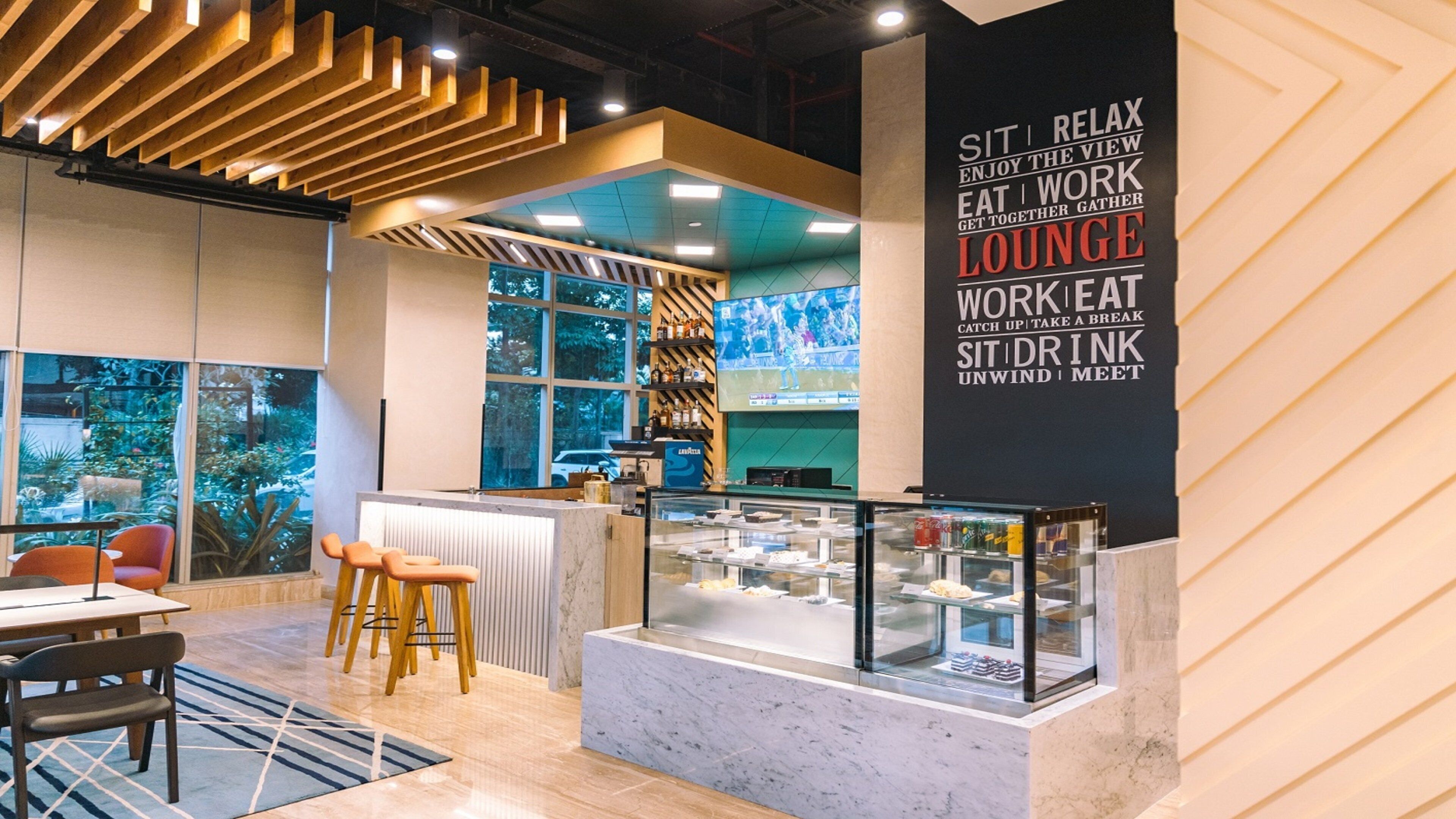A modern lounge area with seating, a counter with a glass display, and a wall with motivational text.