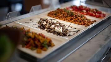 Ein reichhaltiges Buffet mit verschiedenen Speisen, darunter Salate, Früchte und Nüsse.