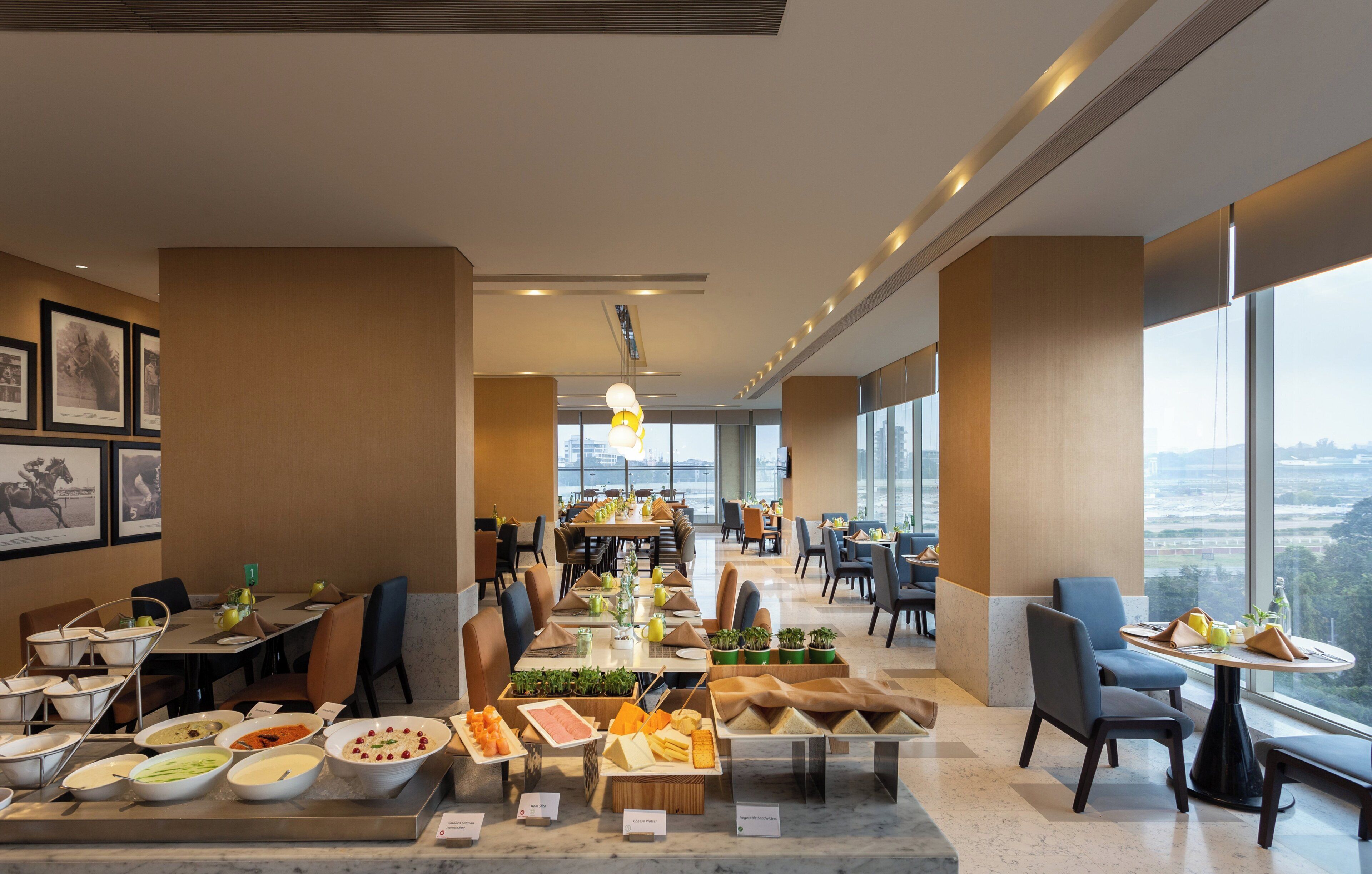 A spacious dining area with multiple tables, chairs, and a variety of food options displayed.