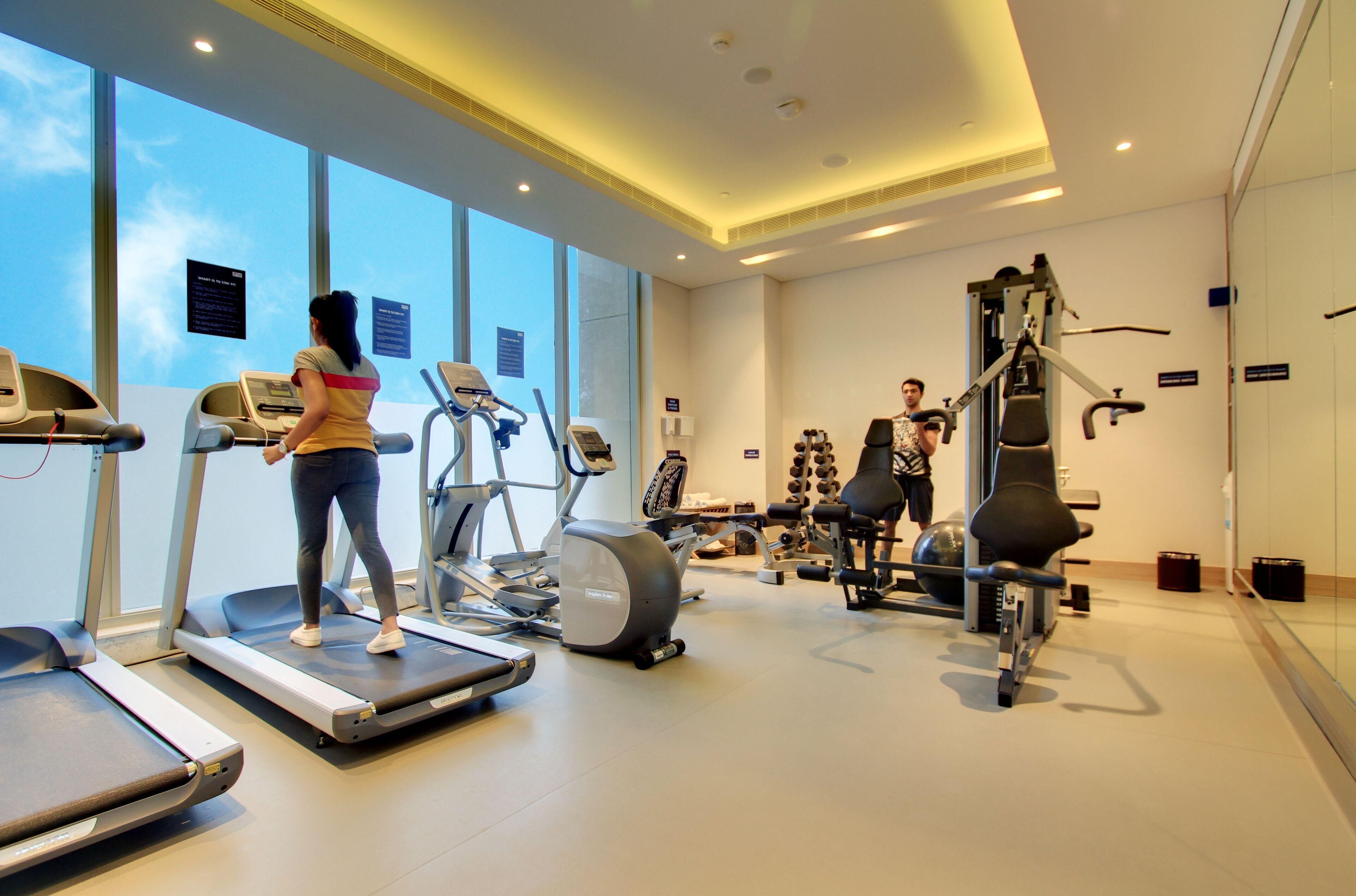 Un gimnasio moderno con cintas de correr, elípticas y equipo de levantamiento de pesas.
