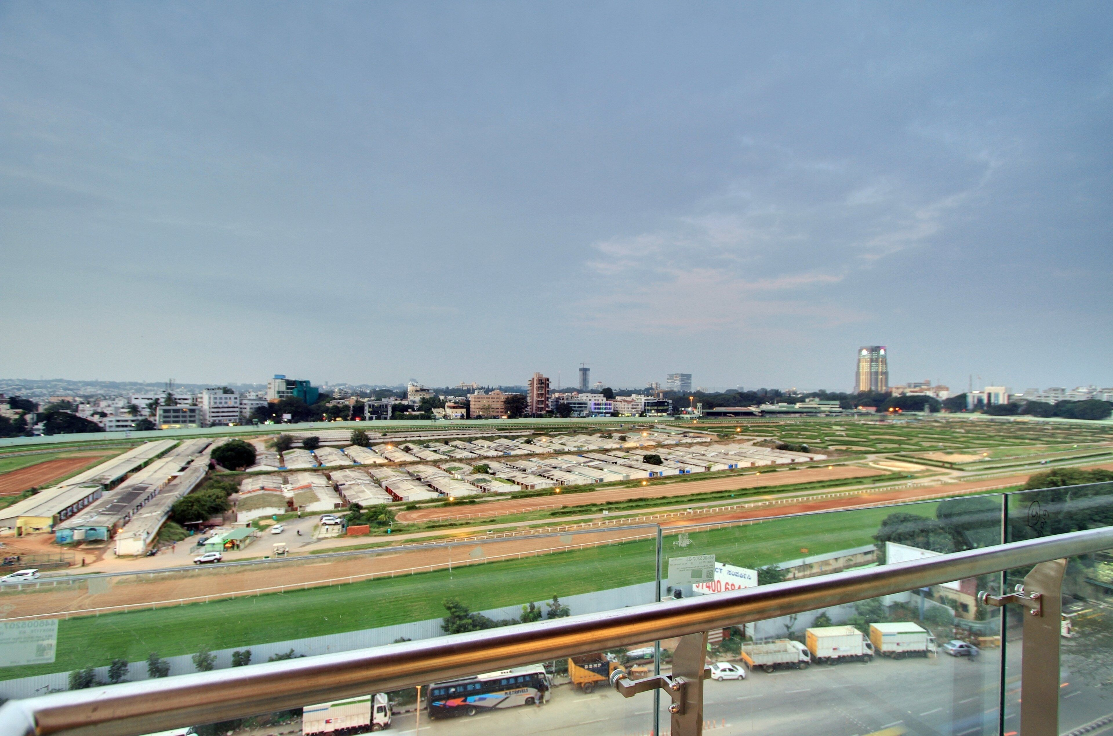 Vista de un paisaje urbano con un espacio abierto, posiblemente un campo deportivo, y edificios al fondo.