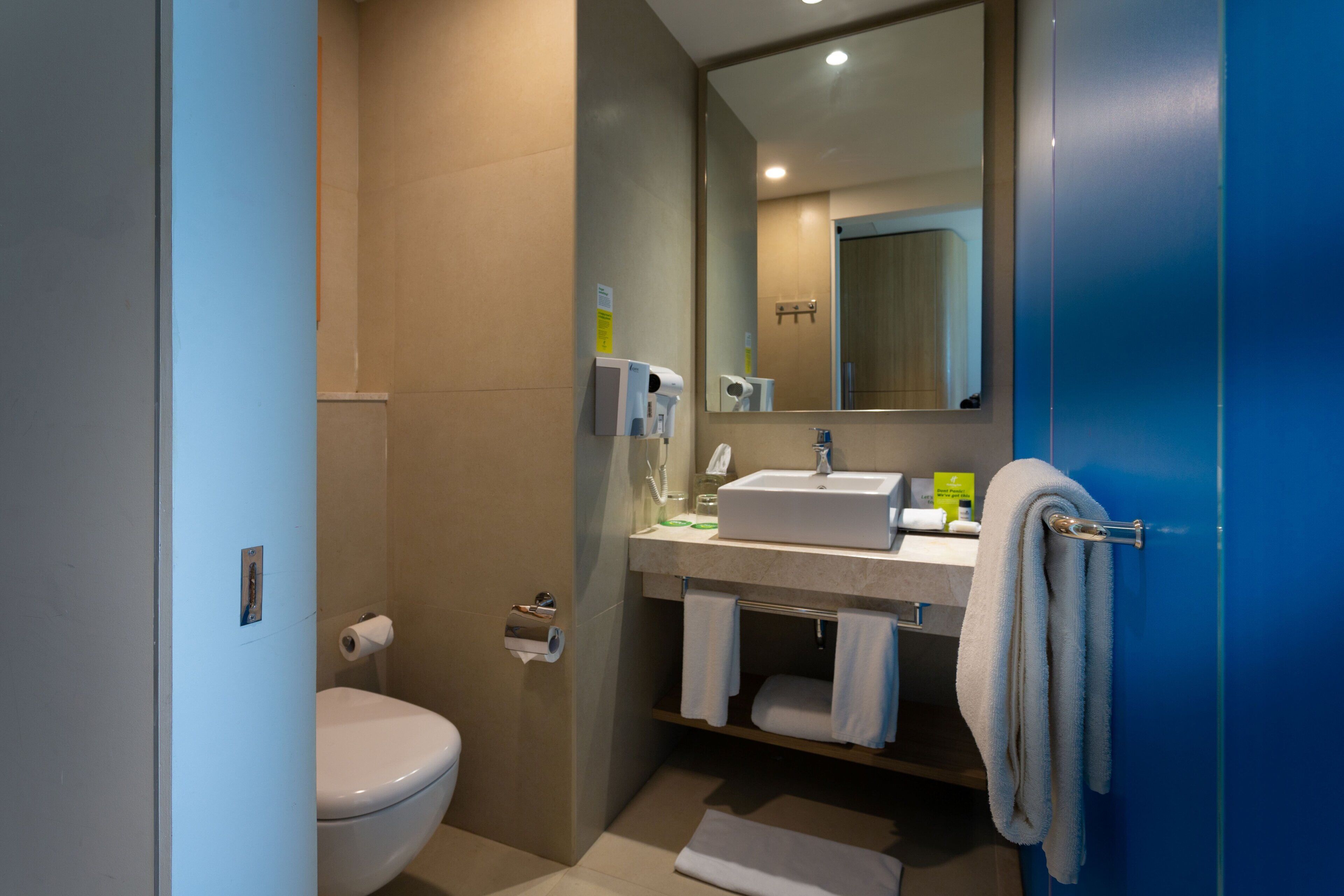 A modern bathroom with a toilet, sink, and mirror.