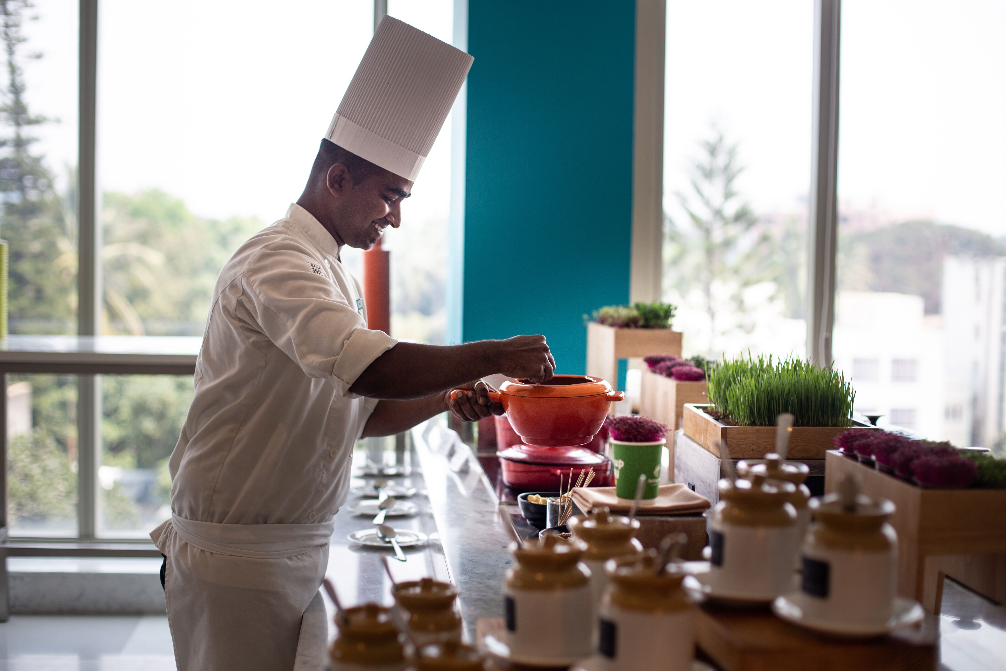 A chef in a white uniform preparing food at a counter with various kitchen utensils and containers.