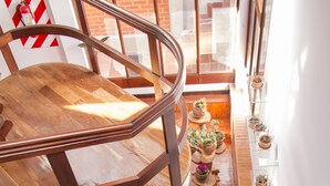A spacious indoor area with a wooden staircase, seating arrangements, and potted plants. - Qhini Hotel Boutique (La Paz)