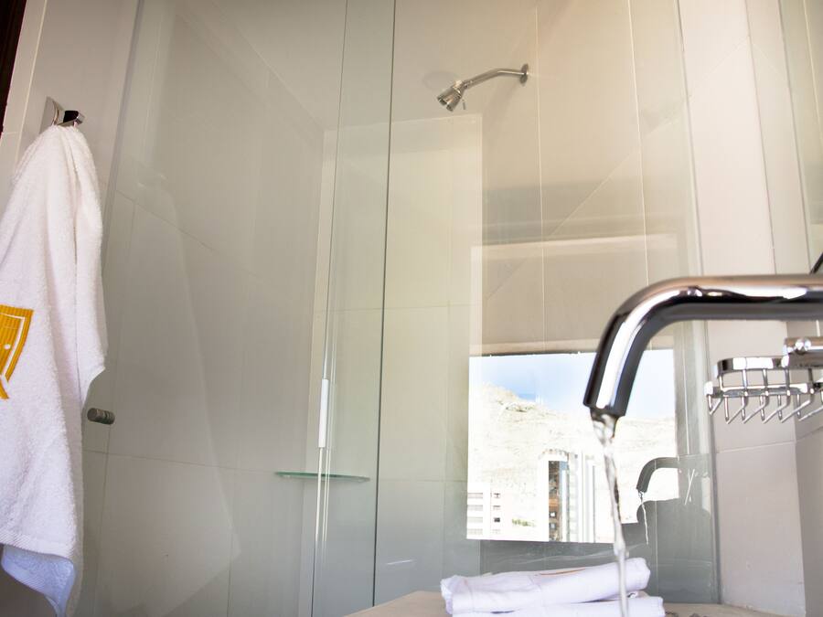 Un baño moderno con cabina de ducha de vidrio, un ventanal y un perchero para toallas.